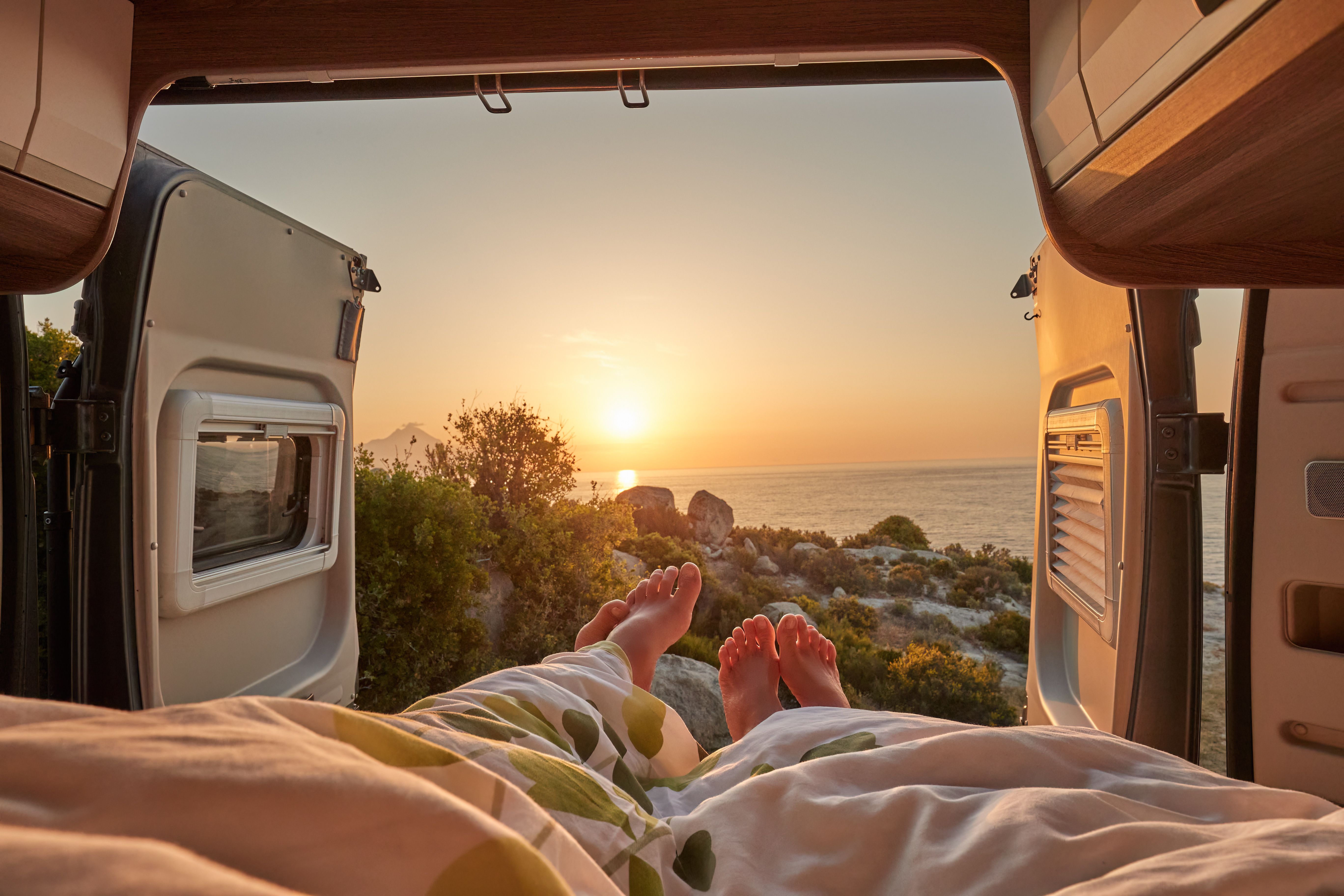 Uitzicht vanuit het bed achterin een van, met de zon die opkomt boven zee